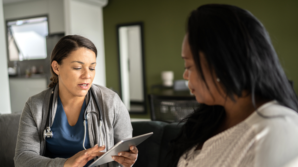 A clinician talking to a patient while inputting data into a tablet.